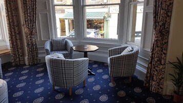 Una habitación con dos sillones a cuadros, una pequeña mesa redonda y una alfombra estampada.