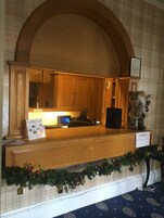 Una recepción con un mostrador de madera, una computadora y un cartel que indica 'CASH ONLY'.