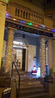 Entrada del Hotel George & Abbot's con luces decorativas y una figura de Papá Noel.
