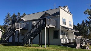 Ein zweistöckiges Haus mit Balkon, Treppe und Veranda.