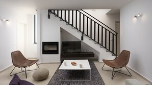 A modern living room with a staircase, a fireplace, and two brown chairs. - Villa Krnica (Marcana)