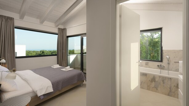 A modern bedroom with a large bed, a bedside table, and a view of the outdoors. - Villa Krnica (Marcana)