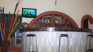 A bar area with a marble countertop, three stools, and a television displaying a nature scene. - The Noble Place (Calabar)