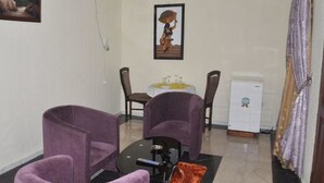 A small, furnished room with two purple armchairs, a small table, and a refrigerator. - The Noble Place (Calabar)