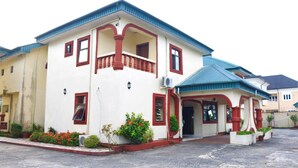 A two-story building with a balcony, a covered entrance, and a small garden area with potted plants. - The Noble Place (Calabar)