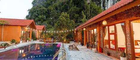 A pool area with a clear view of the surrounding landscape, including a mountain and a building with a red roof.