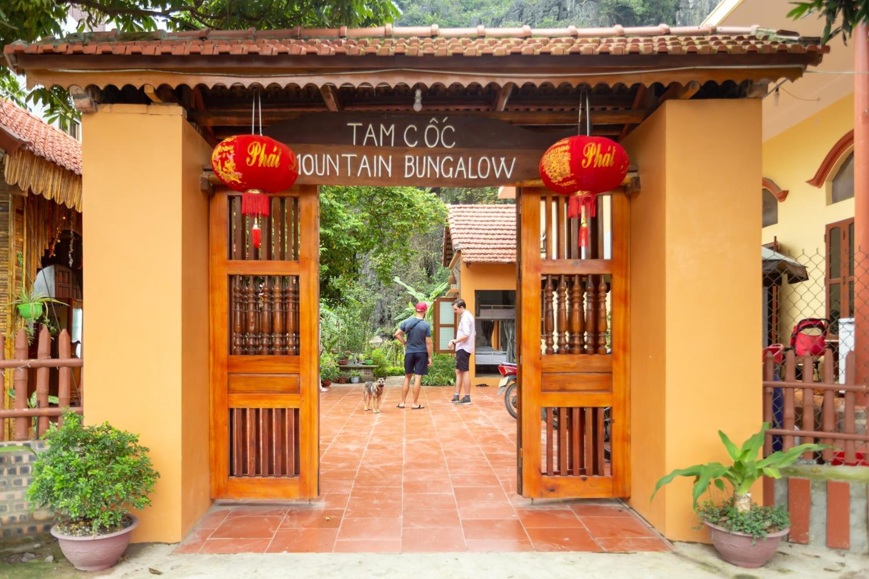 The entrance to Tam Cốc Mountain Bungalow with a traditional wooden gate and a sign above.