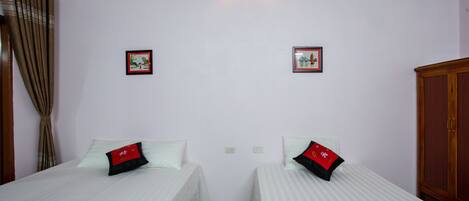A hotel room with two beds, a wall-mounted light, and two framed pictures.