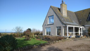 A house with a sloped roof, large windows, and a stone wall surrounding the property. - Aurora B&B (Thurso)