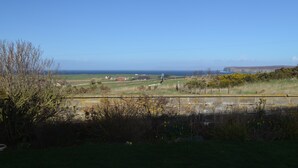 A rural landscape with fields, a fence, and distant buildings. - Aurora B&B (Thurso)