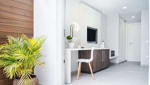 A modern bathroom with a wooden panel wall, a white sink with a mirror, a potted plant, and a white chair.