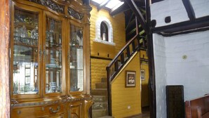 A wooden cabinet with glass doors, a staircase, and a wall with a framed picture. - The Bridge To Ecuador (Pomasqui)