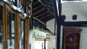 A spacious room with a wooden cabinet, a dining table with chairs, and a tiled floor. - The Bridge To Ecuador (Pomasqui)