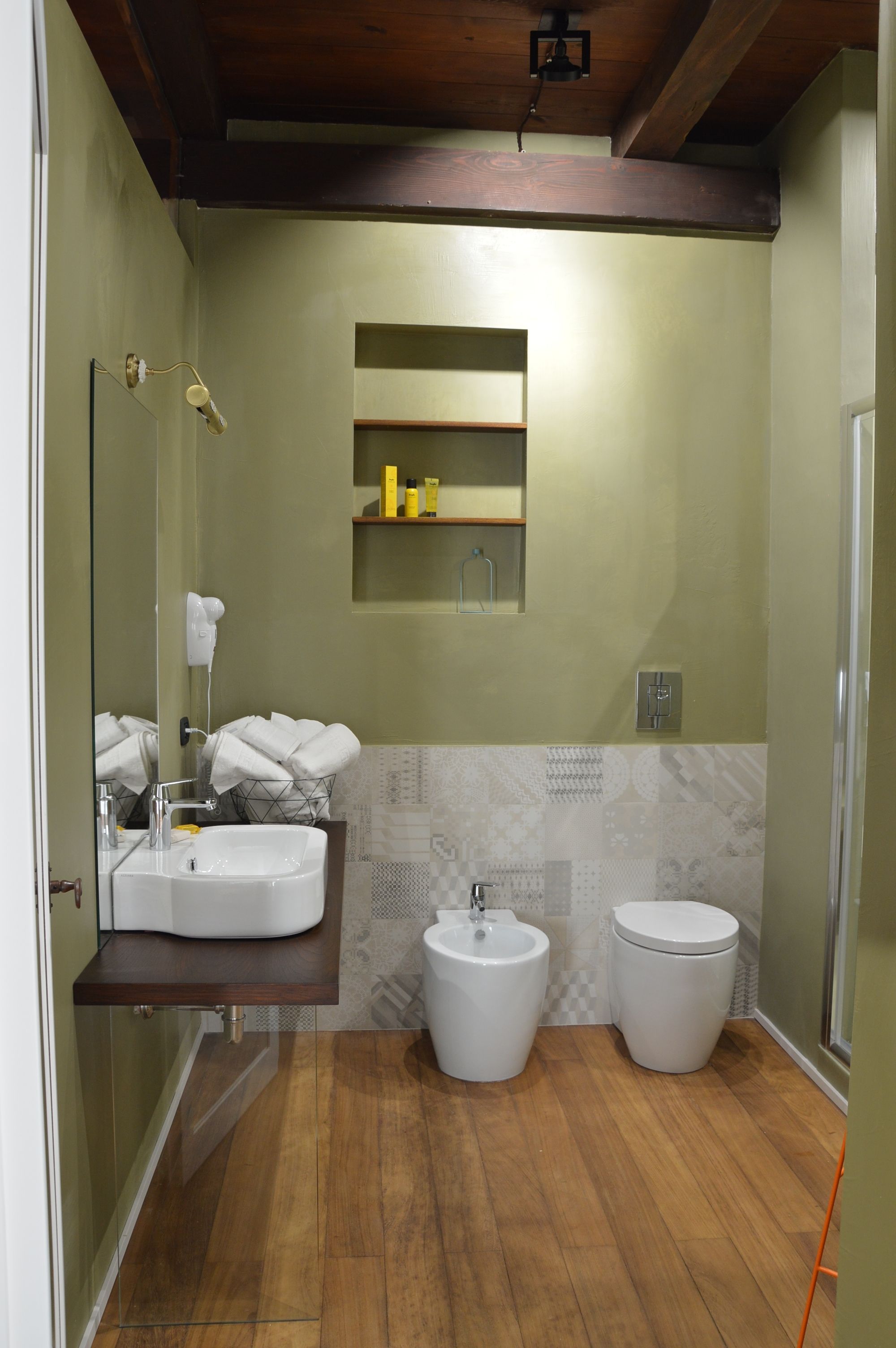Une salle de bain avec un plancher en bois, un lavabo, un bidet et un miroir.