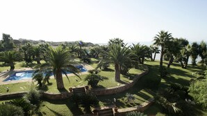 A landscaped garden with palm trees, a swimming pool, and a stone pathway. - CasaRealia (Agrigento)