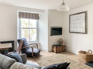 A modern living room with a large window, a television, a rustic vase, and a woven basket.