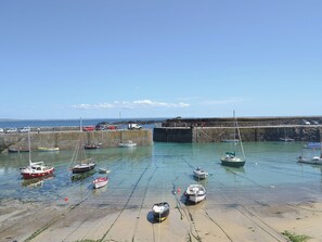 A harbor with various boats docked, a stone breakwater, and a clear sky.