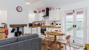 Une cuisine moderne avec un coin repas, un canapé et une vue sur l’extérieur, visible à travers la porte.
