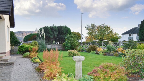 A well-maintained garden with a variety of plants and a stone feature in the center. - 4 bedroom accommodation in Keswick (Keswick)