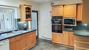 A modern kitchen with wooden cabinets, a built-in oven, and a dishwasher. - 4 bedroom accommodation in Keswick (Keswick)