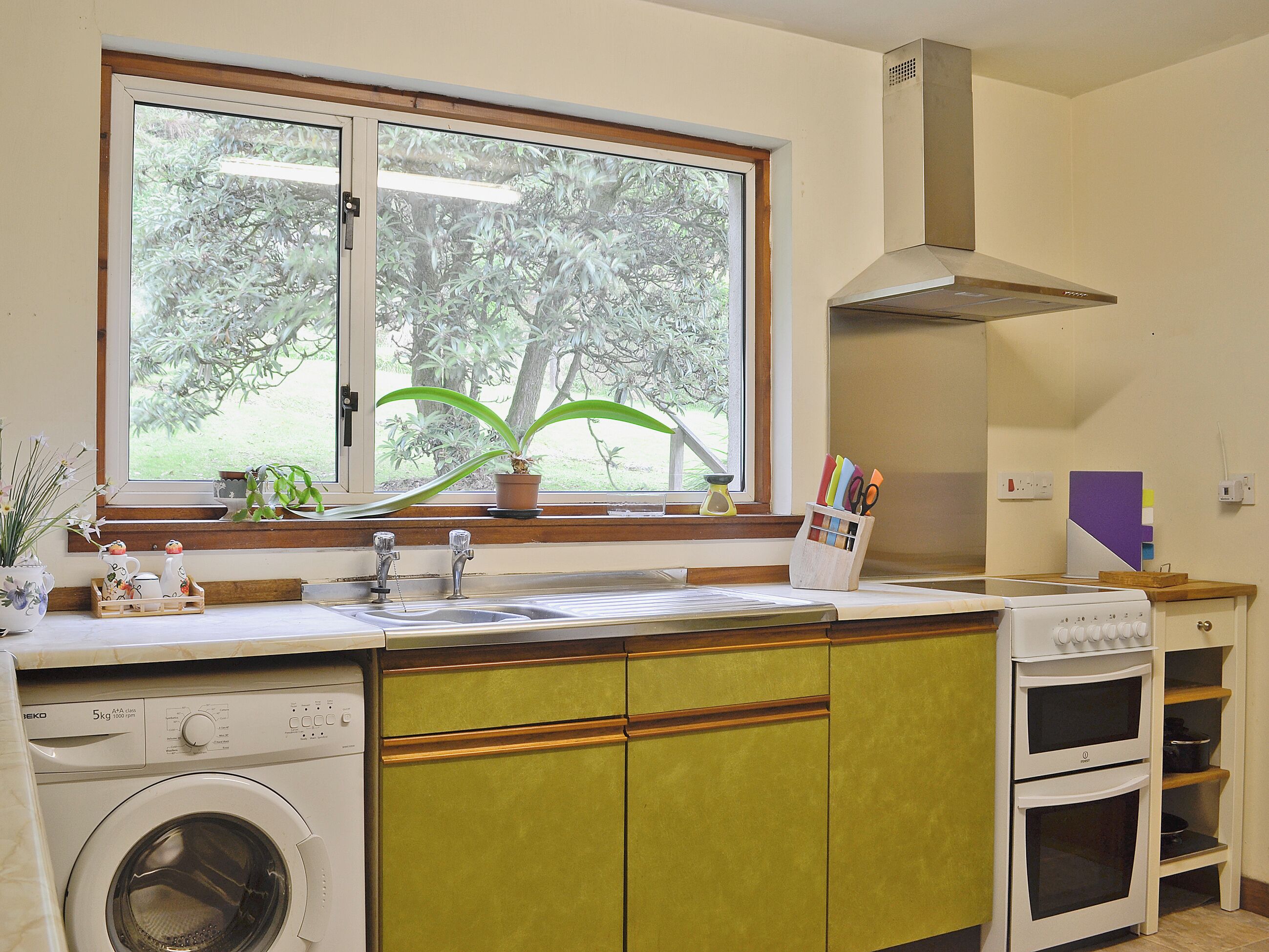Une cuisine avec une fenêtre, un lave-linge et une cuisinière.