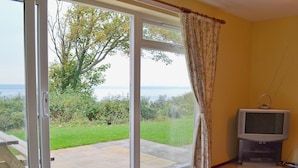 Una habitación con puerta de vidrio corredera que da a un patio con vista al mar.