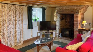 Ein Wohnzimmer mit Fernseher, rotem Sofa und Kamin.
