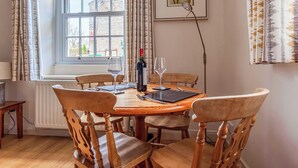 Ein Esszimmer mit Holztisch, sechs Stühlen, einer Weinflasche und zwei Weingläsern.