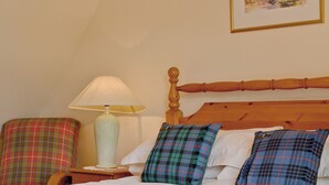 A neatly made bed with plaid pillows, a wooden headboard, a bedside table with a lamp, and a plaid armchair. - 2 bedroom accommodation in Glenelg, near Kyle of Lochalsh (Glenelg, near Kyle of Lochalsh)