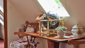 A cozy room with a wooden table, a globe, a potted plant, and a chair with a floral cushion. - 2 bedroom accommodation in Glenelg, near Kyle of Lochalsh (Glenelg, near Kyle of Lochalsh)