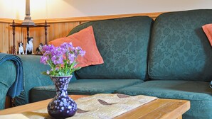 A living room with a green sofa, a wooden coffee table, a purple vase with flowers, and a lamp in the background. - 2 bedroom accommodation in Glenelg, near Kyle of Lochalsh (Glenelg, near Kyle of Lochalsh)