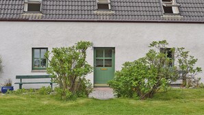 A two-story building with a grey tiled roof, a green door, and two windows. - 2 bedroom accommodation in Glenelg, near Kyle of Lochalsh (Glenelg, near Kyle of Lochalsh)