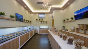 A buffet area with multiple food stations, wooden paneling, and shelves with plants. - Isida Hotel (Chania)