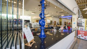 A reception area with a blue decorative piece, a counter, and a signboard. - Isida Hotel (Chania)