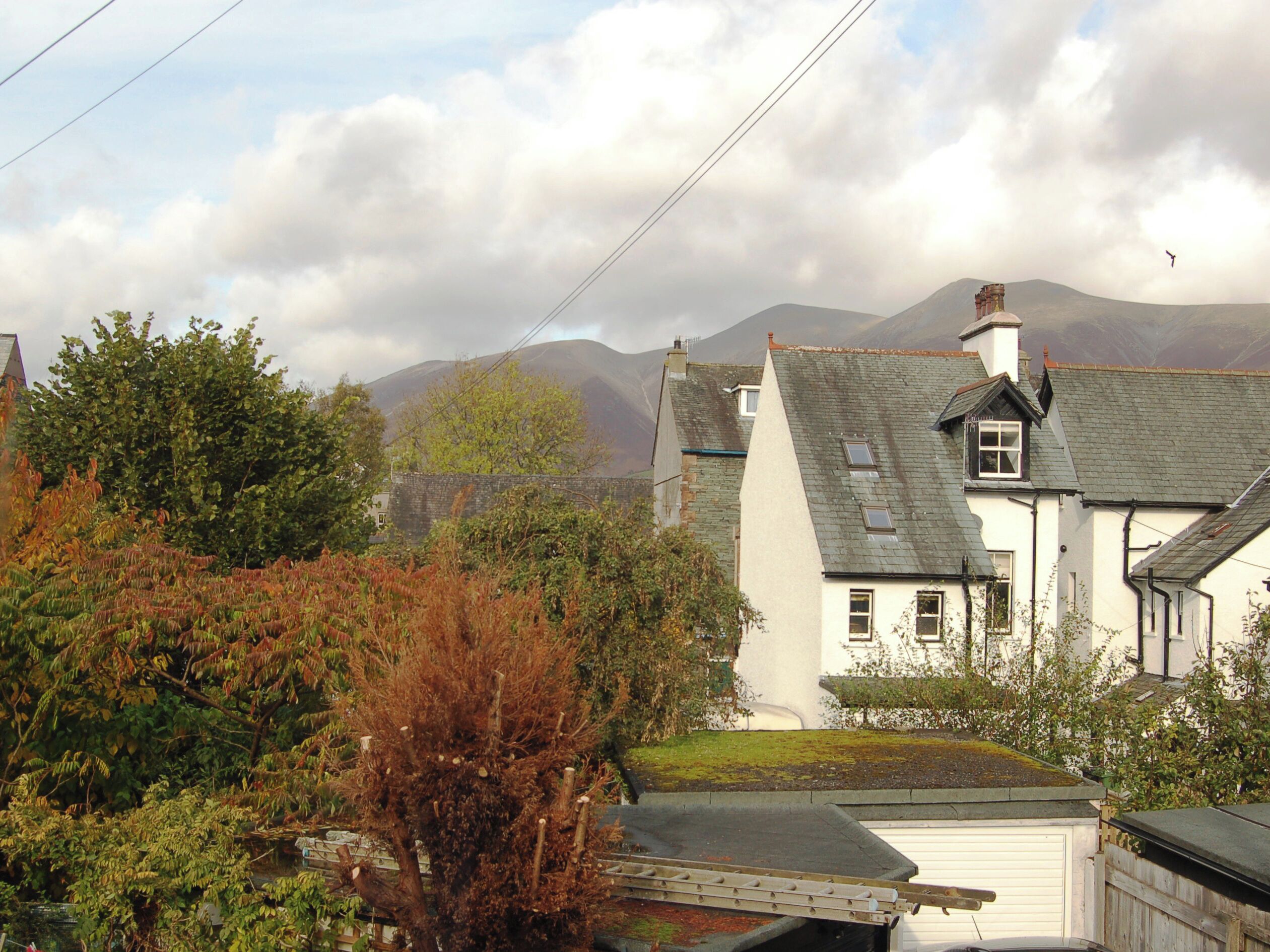 A white house with a sloped roof, a visible chimney, and a small window.