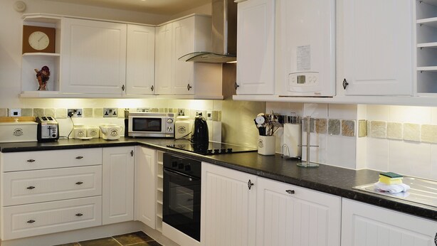 A kitchen with white cabinets, a microwave, a toaster, and a stove.