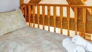 A bed with a patterned bedspread, wooden headboard, and two rolled towels. - 2 bedroom accommodation in Tynlon, near Rhosneigr (Tynlon, near Rhosneigr)