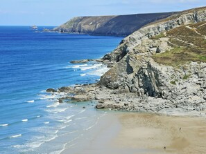 Un paysage côtier caractérisé par des falaises rocheuses et une plage de sable.