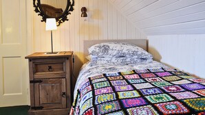 A bedroom with a wooden dresser, a bedside lamp, a quilt, and a mirror on the wall. - 2 bedroom accommodation in Lower Harrapool, near Broadford (Lower Harrapool, near Broadford)