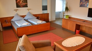 A modern bedroom with a wooden bed, a sofa, a small table, and a TV. - Hotel Garni Sebastian (Kirrweiler)