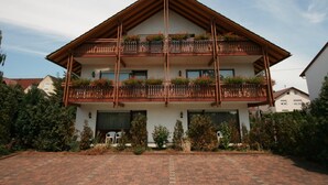 A two-story building with a wooden balcony and flower boxes. - Hotel Garni Sebastian (Kirrweiler)