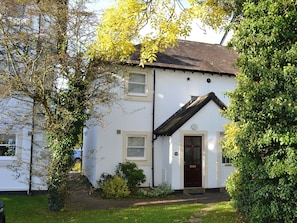 A white two-story house with a dark roof, a front door, and a small porch. - Elm Court 18 has the advantage of being a semi-detached house. (Keswick)