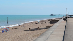 A pebbled beach with a concrete walkway and a pier in the distance. - 6 bedroom accommodation in St Margarets Bay, Dover (St Margarets Bay, Dover)