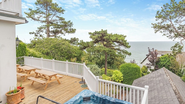 A deck with a hot tub, wooden furniture, and a view of the sea. - 6 bedroom accommodation in St Margarets Bay, Dover (St Margarets Bay, Dover)