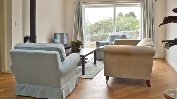 Ein Wohnzimmer mit einer Couch, einem Sessel und einem Fernseher.