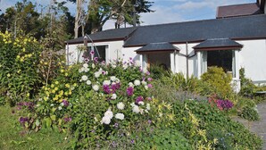 Ein Haus mit einem Garten voller verschiedener Blumen und einem klaren Himmel.