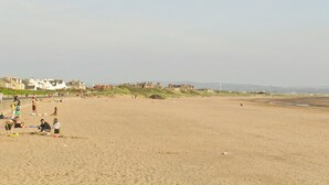 Een breed zandstrand met mensen die diverse activiteiten ondernemen.