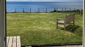 A grassy outdoor area with a bench, a wooden fence, and a view of the sea. - 3 bedroom accommodation in Downderry, near Looe (Downderry, near Looe)
