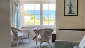 A room with a view of the sea, wicker furniture, a framed picture, and a sofa. - 3 bedroom accommodation in Downderry, near Looe (Downderry, near Looe)
