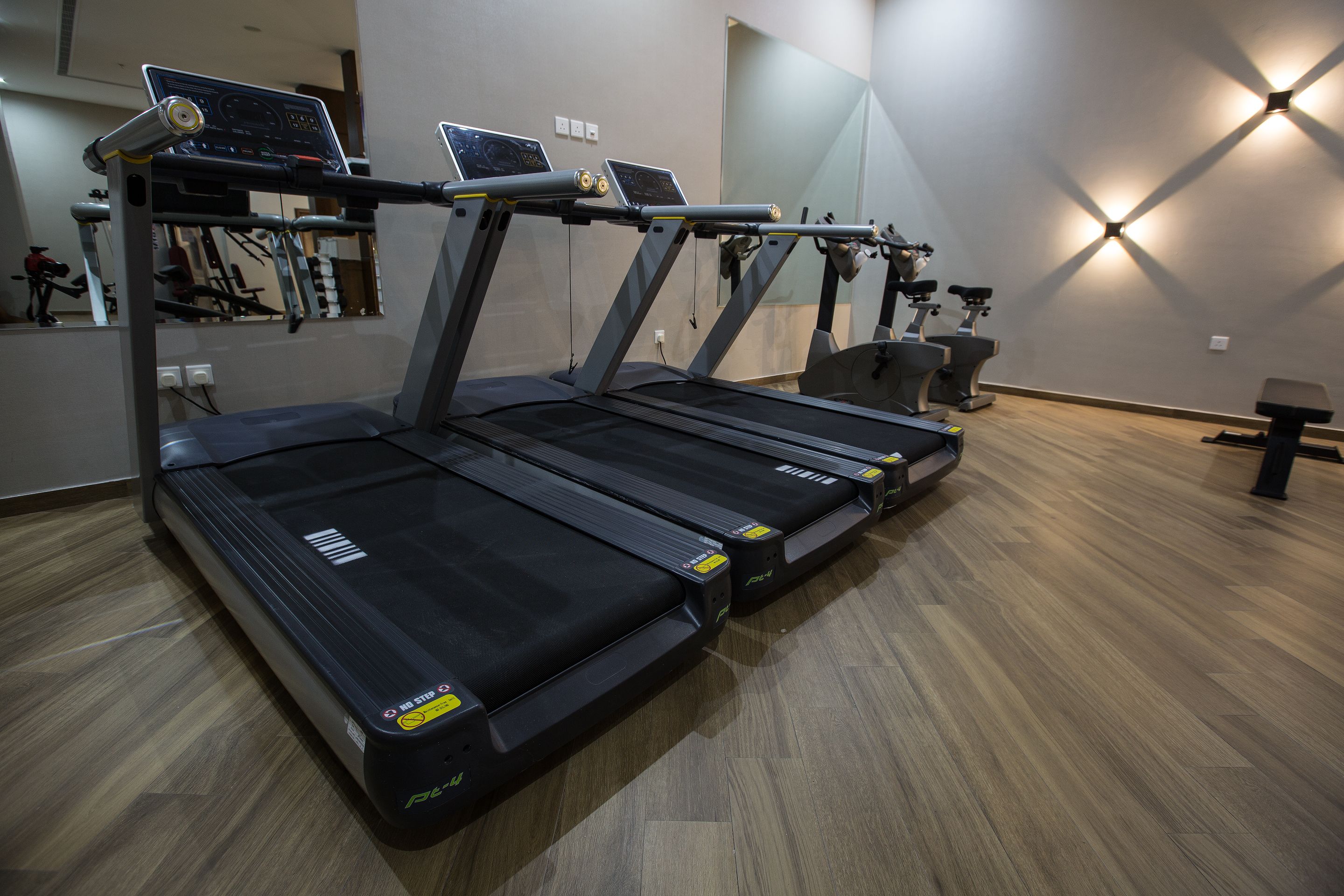 A gym with multiple treadmills, exercise bikes, and a mirrored wall.